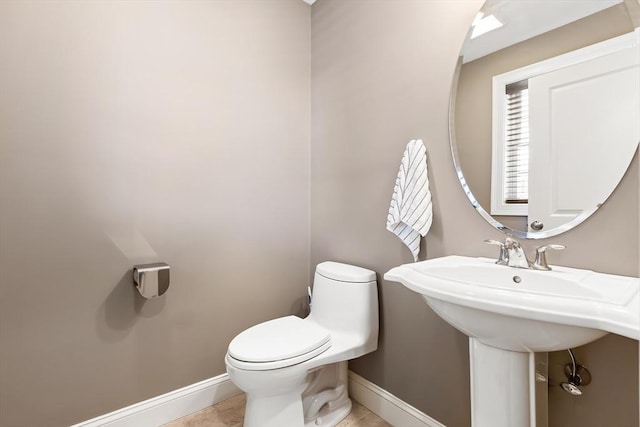 bathroom featuring a sink, baseboards, tile patterned floors, and toilet