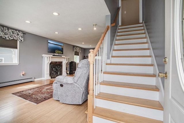 374 Forest St, Raynham, MA 02767 - staircase with recessed lighting, wood finished floors, a fireplace, plenty of natural light, and a baseboard heating unit