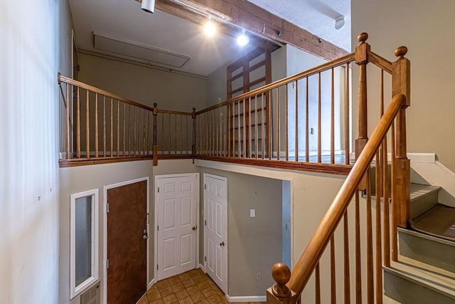 stairs with a high ceiling, rail lighting, and tile patterned flooring