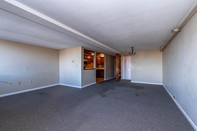 spare room with an inviting chandelier, dark carpet, and a textured ceiling