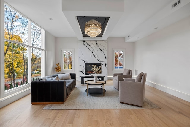 living room with light hardwood / wood-style floors, a high end fireplace, and a chandelier