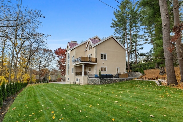 back of house with a yard and a balcony