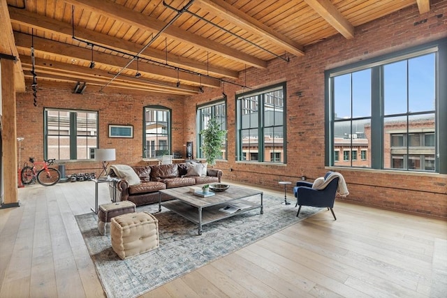 interior space featuring brick wall, beam ceiling, light hardwood / wood-style flooring, and wood ceiling