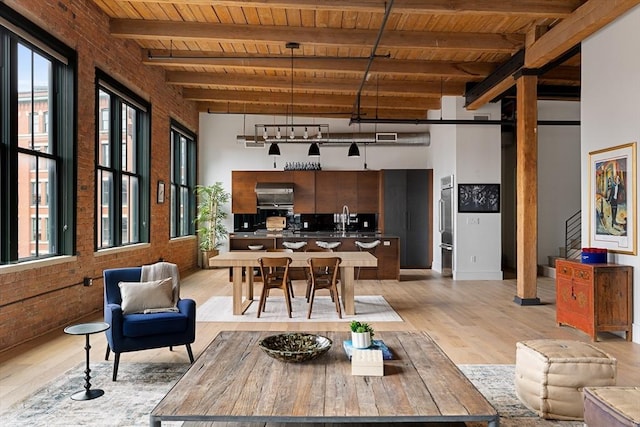 dining area featuring wood ceiling, brick wall, beamed ceiling, and sink