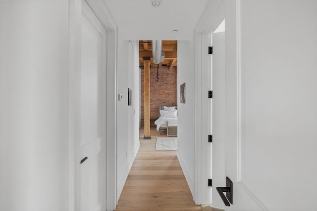 hall featuring brick wall and light hardwood / wood-style floors