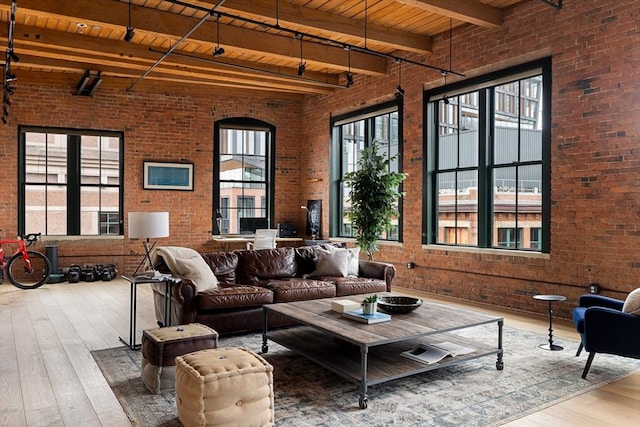 living room featuring brick wall, beam ceiling, and hardwood / wood-style flooring