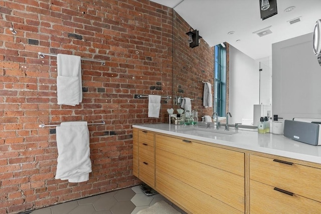 bathroom with brick wall, tile patterned flooring, and vanity