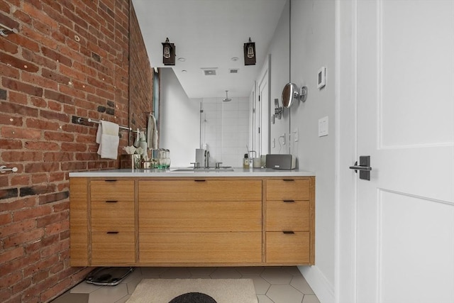 bathroom with vanity, tile patterned floors, and brick wall