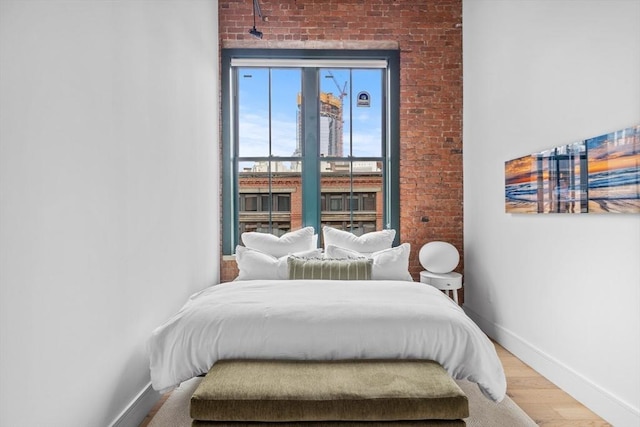 bedroom with brick wall and light hardwood / wood-style floors