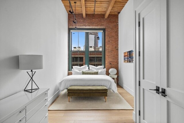 bedroom with brick wall, light wood-type flooring, wood ceiling, and beam ceiling