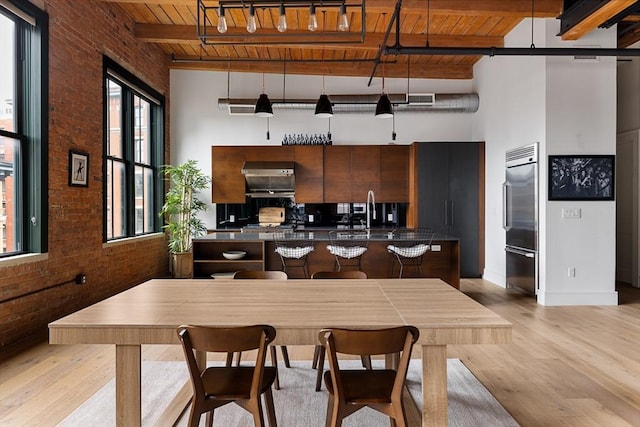 kitchen featuring brick wall, wooden ceiling, and beam ceiling