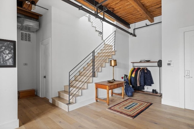 stairway featuring beamed ceiling, wood ceiling, and hardwood / wood-style floors