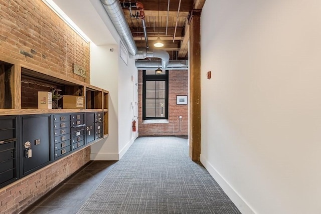 hallway with brick wall, a towering ceiling, and mail boxes