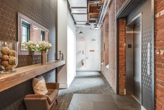 corridor featuring brick wall and elevator