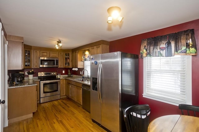 kitchen featuring light stone counters, appliances with stainless steel finishes, light hardwood / wood-style floors, and sink