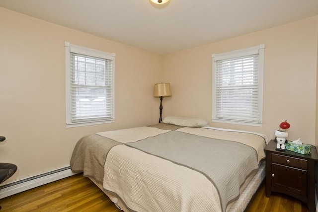 bedroom with a baseboard heating unit and wood-type flooring