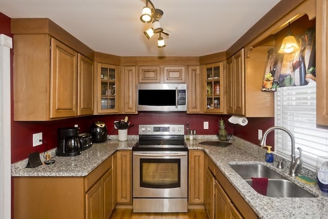 kitchen featuring stainless steel appliances, light stone countertops, sink, and hanging light fixtures