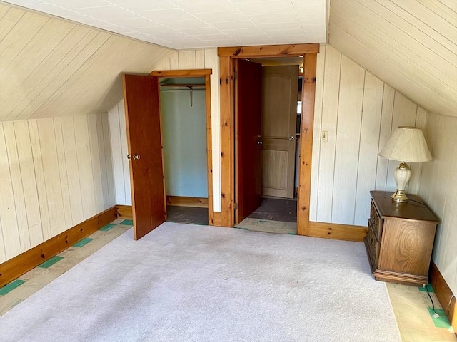 additional living space with lofted ceiling, light colored carpet, and wooden walls