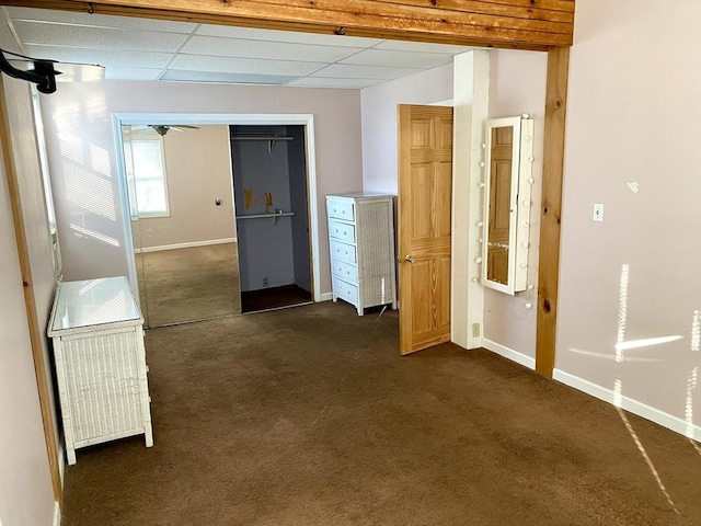 hall with dark carpet and a paneled ceiling