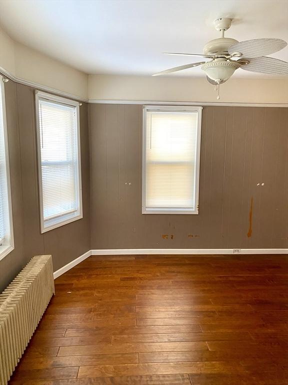 unfurnished room featuring ceiling fan, radiator, and dark hardwood / wood-style flooring