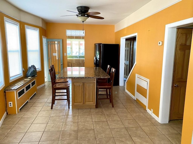 dining space with sink, light tile patterned floors, and ceiling fan