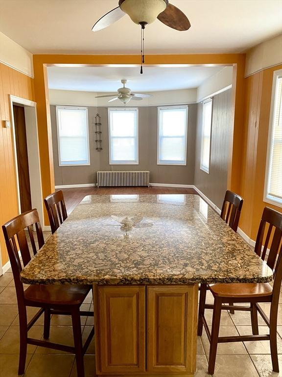 dining space with radiator, light tile patterned floors, and wood walls