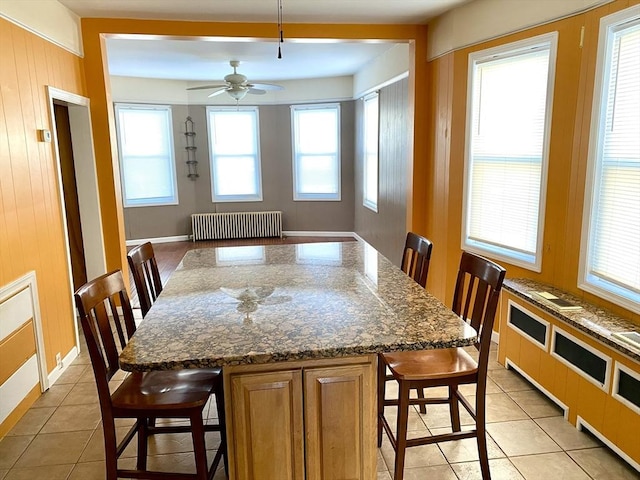 dining space with radiator heating unit, ceiling fan, and light tile patterned floors