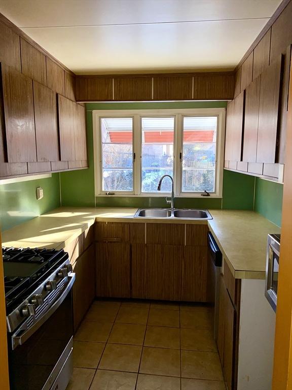 kitchen with sink, gas range, plenty of natural light, and light tile patterned floors