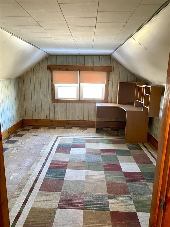 bonus room featuring lofted ceiling and wood walls