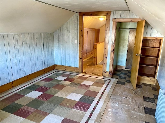 additional living space featuring wooden walls and vaulted ceiling