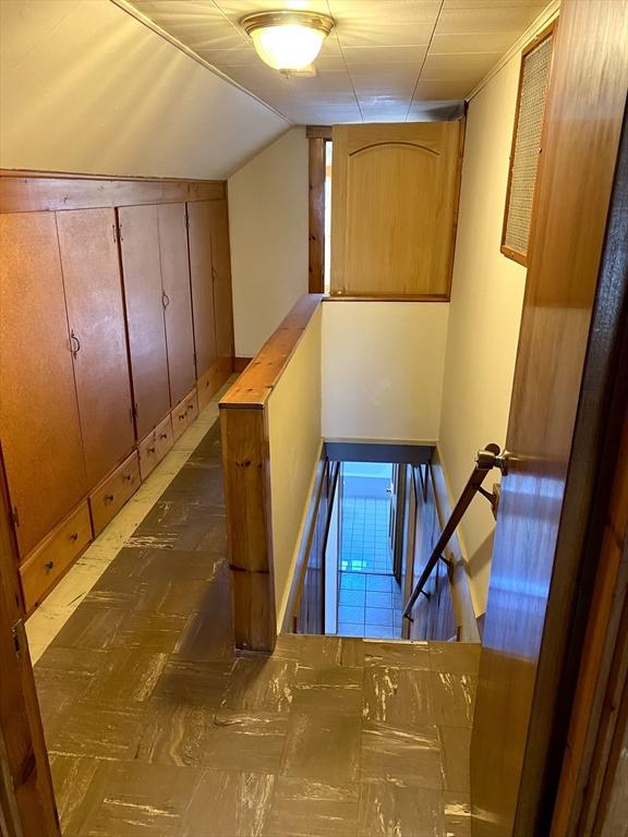 stairs with vaulted ceiling and wooden walls