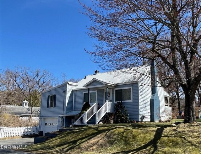view of front of home with fence, an attached garage, aphalt driveway, a front yard, and a chimney