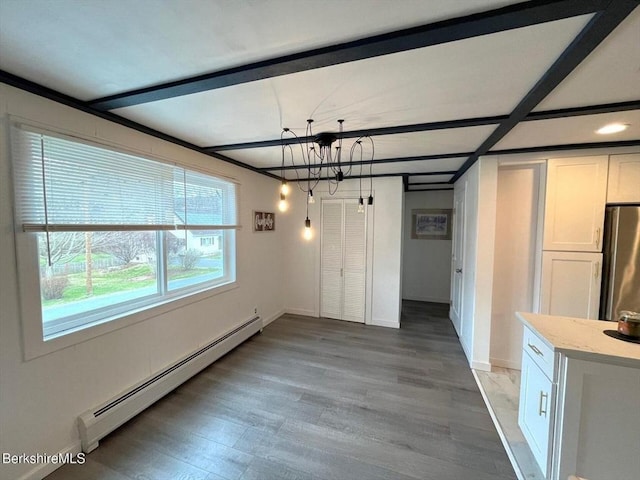 unfurnished dining area with a baseboard heating unit, baseboards, beamed ceiling, light wood finished floors, and a notable chandelier