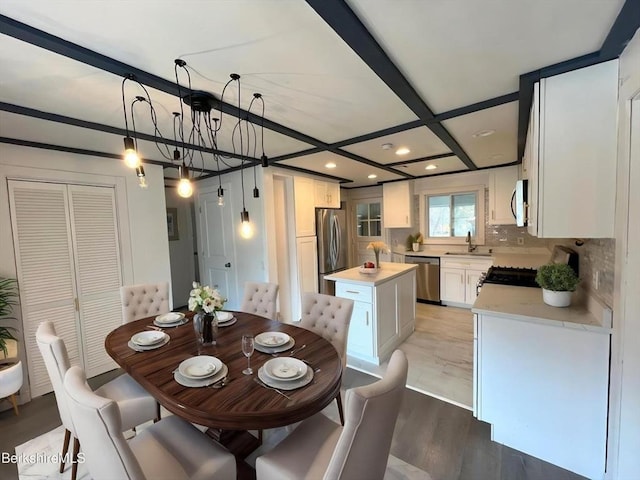 dining area with coffered ceiling, a notable chandelier, light wood-style flooring, and recessed lighting