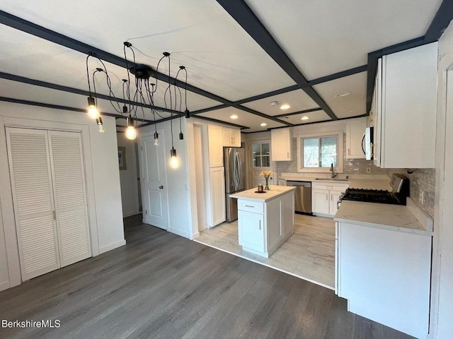 kitchen featuring a center island with sink, light wood-style flooring, decorative backsplash, and appliances with stainless steel finishes