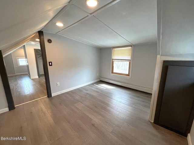 bonus room featuring baseboards, baseboard heating, wood finished floors, and vaulted ceiling