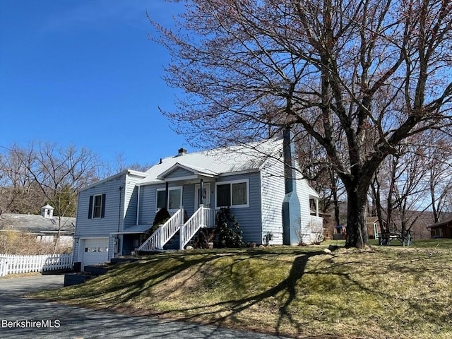 view of front of home featuring fence, an attached garage, a chimney, a front lawn, and driveway
