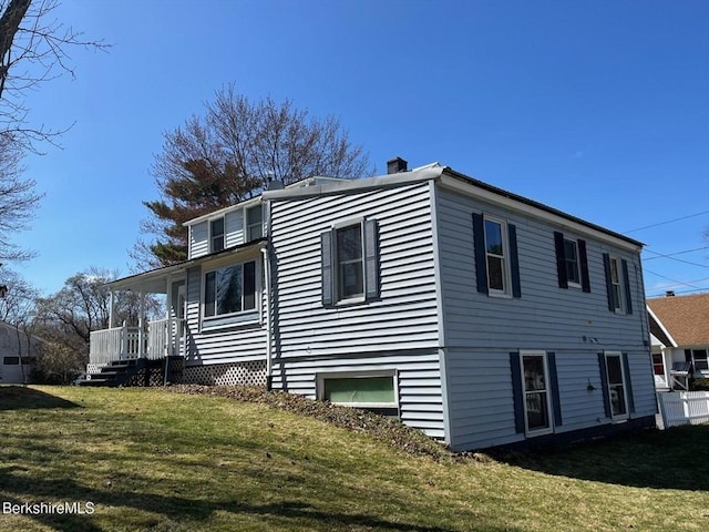 exterior space with a lawn, a chimney, and covered porch