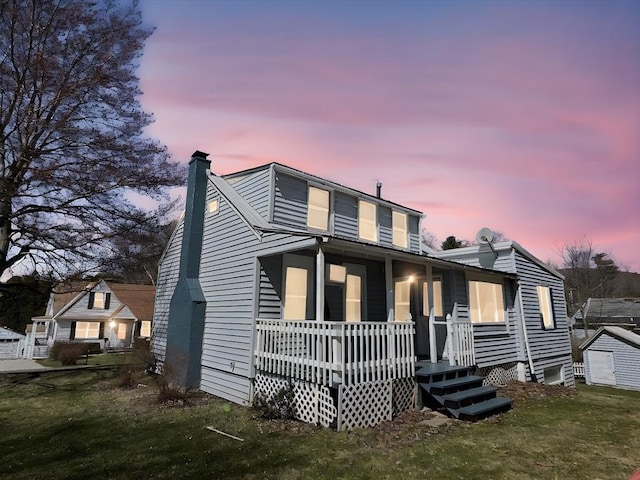 view of front of property with a lawn, a chimney, and covered porch