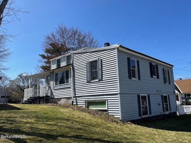 exterior space featuring a porch, a yard, and a chimney