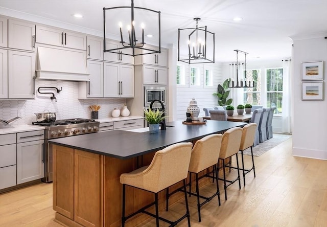 24 Owls Nest Unit 11, Plymouth, MA 02360 - kitchen featuring a notable chandelier, custom range hood, a center island with sink, tasteful backsplash, and appliances with stainless steel finishes