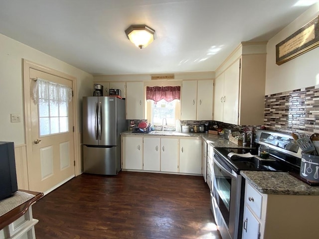 kitchen with dark wood-type flooring, white cabinetry, stainless steel appliances, decorative backsplash, and dark stone counters