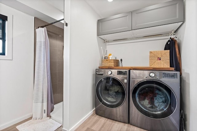clothes washing area featuring washer and dryer, laundry area, baseboards, and light wood-style flooring