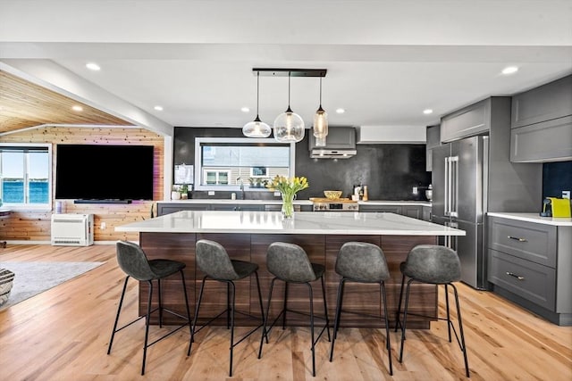 kitchen featuring a kitchen island, a kitchen bar, high quality fridge, a wealth of natural light, and gray cabinetry