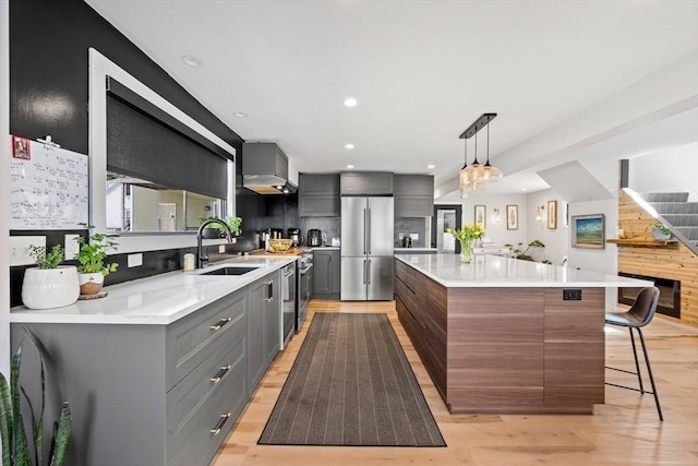 kitchen with light wood-style flooring, a sink, gray cabinets, and high end refrigerator