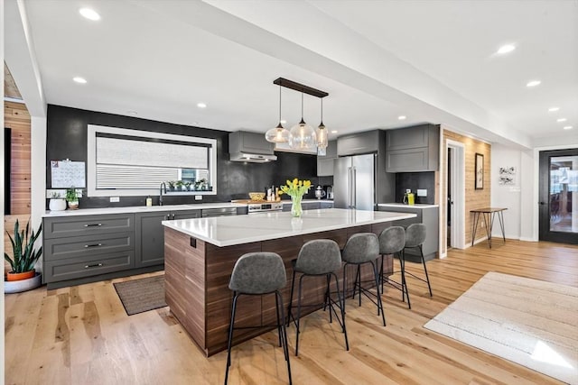 kitchen featuring light countertops, appliances with stainless steel finishes, gray cabinetry, and a kitchen breakfast bar