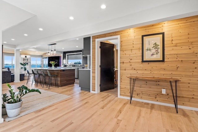 living room featuring recessed lighting, light wood finished floors, and wooden walls