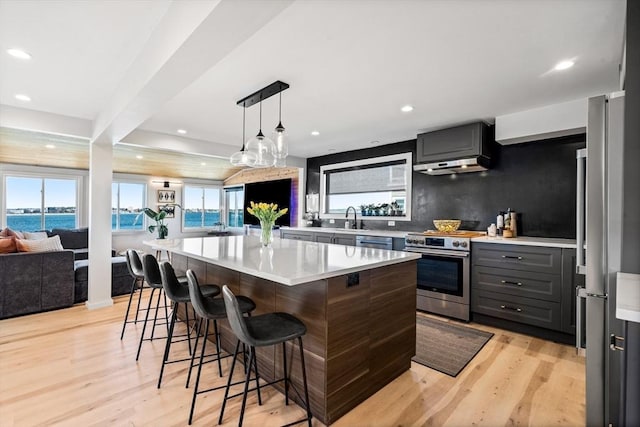 kitchen with a breakfast bar, open floor plan, light countertops, a sink, and stainless steel appliances