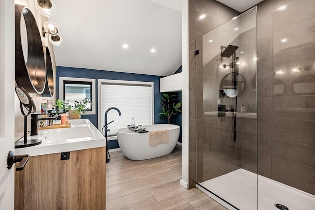 bathroom featuring vanity, walk in shower, vaulted ceiling, and a soaking tub