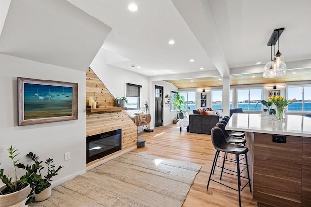 living room with recessed lighting, baseboards, a glass covered fireplace, and light wood finished floors